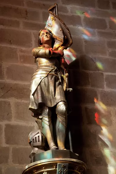 Statue of St. Joan of Arc with coloured light from stained glass, Church of Notre Dame
