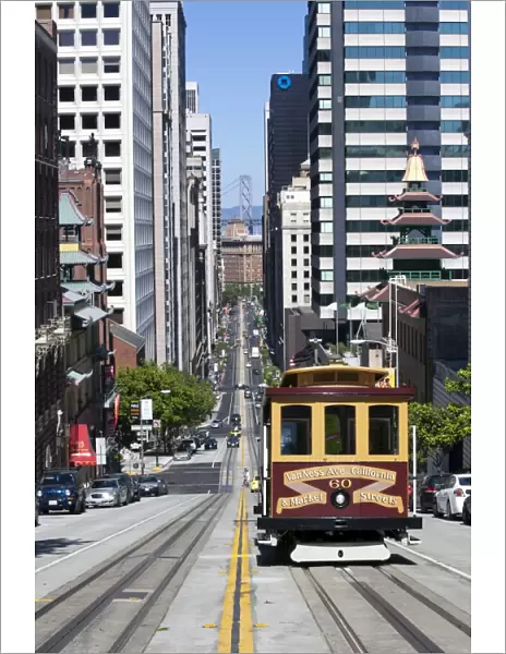Cable car crossing California Street with Bay Bridge backdrop in San Francisco, California, United States of America, North America