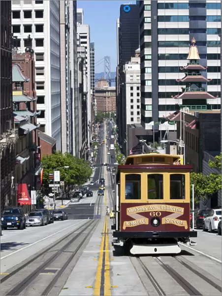 Cable car crossing California Street with Bay Bridge backdrop in San Francisco, California, United States of America, North America
