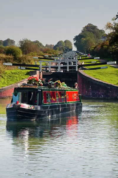 A canal boat leaving the famous series of locks at Caen Hill on the Kennet and Avon Canal, Wiltshire, England, United Kingdom, Europe