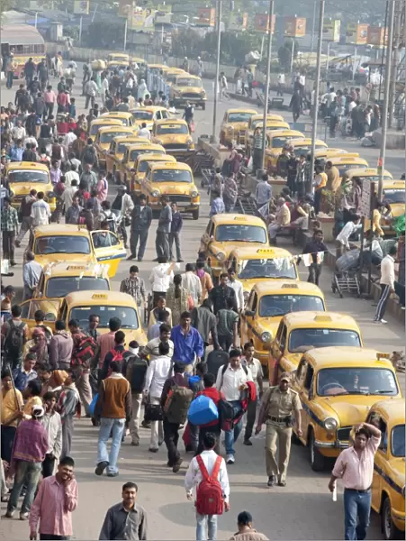 Yellow Kolkata taxis and commuters outside Howrah Railway Station in morning rush hour, Howrah, Kolkata (Calcutta), West Bengal, India, Asia