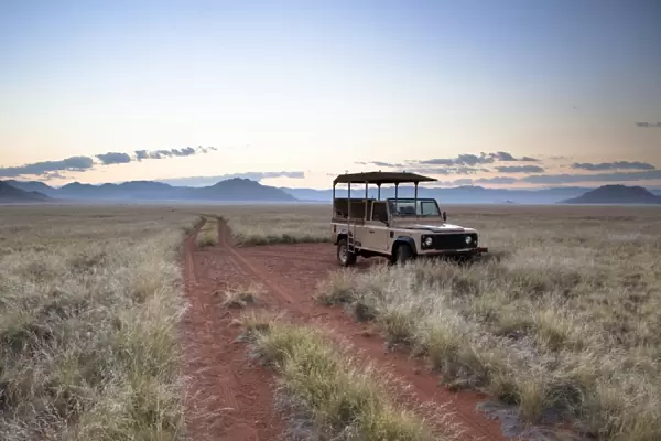 Land rover game vehicle parked by sand road at sunrise, Namib Rand game reserve, Namib Naukluft Park, Namibia, Africa