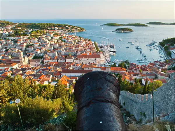 Hvar Fortress cannon and Hvar Town at sunset taken from the Spanish Fort (Fortica), Hvar Island, Dalmatian Coast, Adriatic, Croatia, Europe