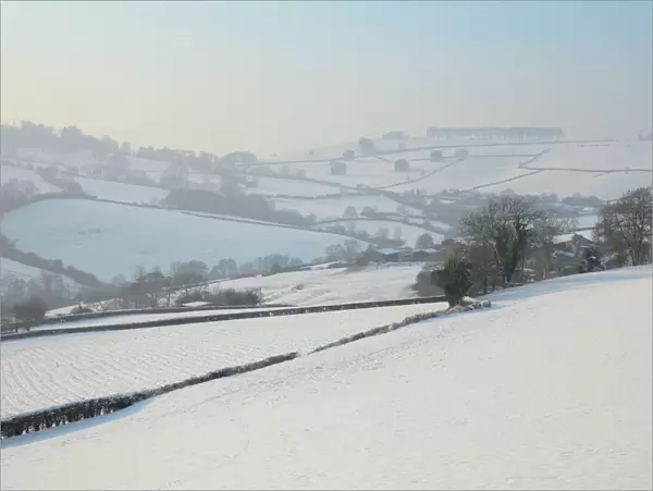 Snow covered hillside pastureland, arable fields and bare trees in winter, Tadwick, Bath and Northeast Somerset, England, United Kingdom, Europe