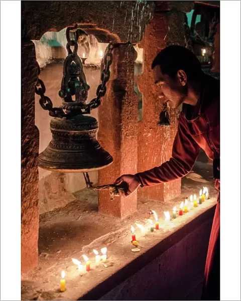 A Buddhist monk rings a prayer bell during the full moon celebrations, Bodhnath stupa, Bodhnath, Nepal, Asia