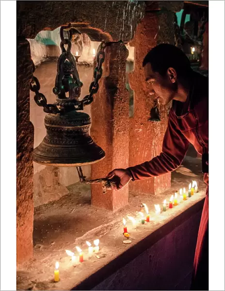 A Buddhist monk rings a prayer bell during the full moon celebrations, Bodhnath stupa, Bodhnath, Nepal, Asia