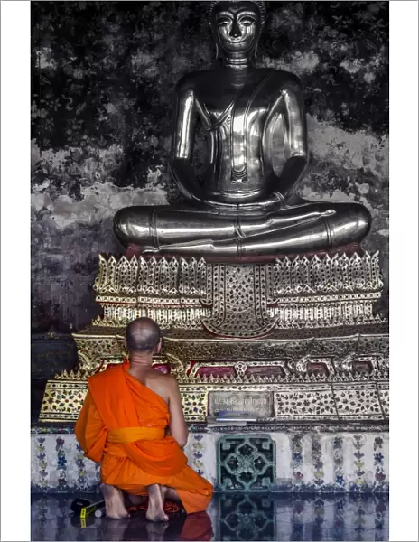 A monk prays in front of a golden Buddha, Wat Suthat, Bangkok, Thailand, Southeast Asia, Asia