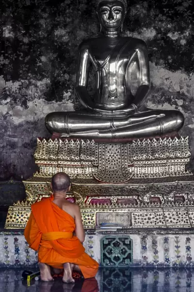 A monk prays in front of a golden Buddha, Wat Suthat, Bangkok, Thailand, Southeast Asia, Asia