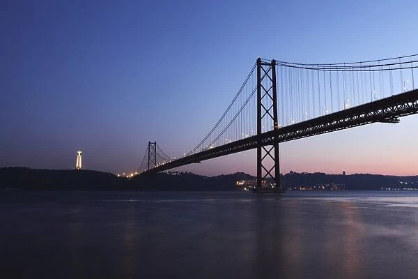 The 25 April Suspension Bridge at dusk over the River Tagus (Rio Tejo), Christus Rei is illuminated at Almada, Lisbon, Portugal, Europe