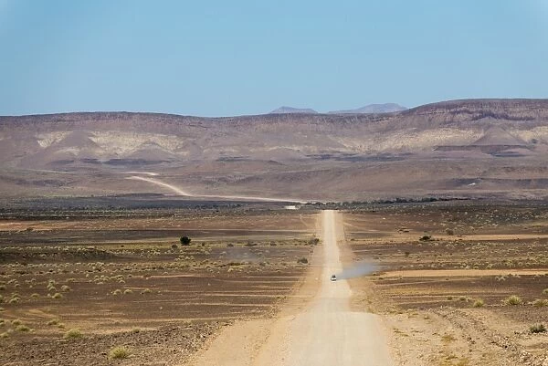 A 4x4 car leaves a cloud of dust as it apporachs along the long dusty road to the Fish River Canyon