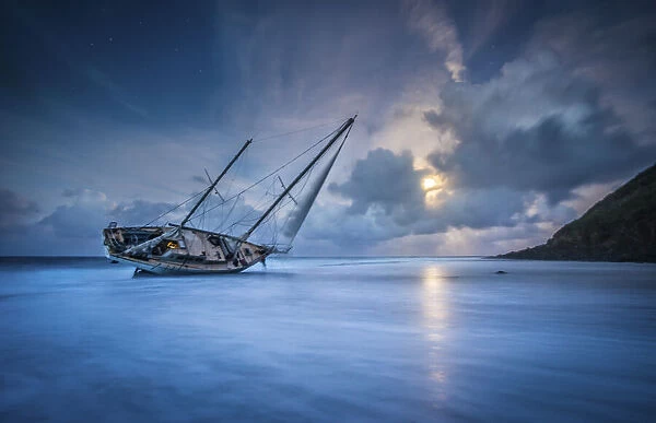 An abandoned sailboat rests on its side at low tide in Moloa a Bay