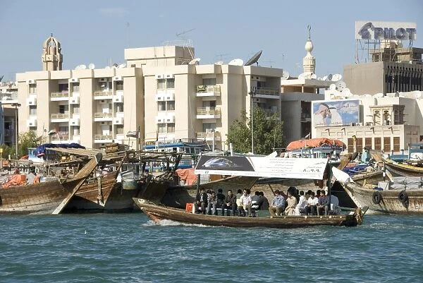 Abra (cross-creek ferry) chugs past dhow wharves and modern buildings of Deira