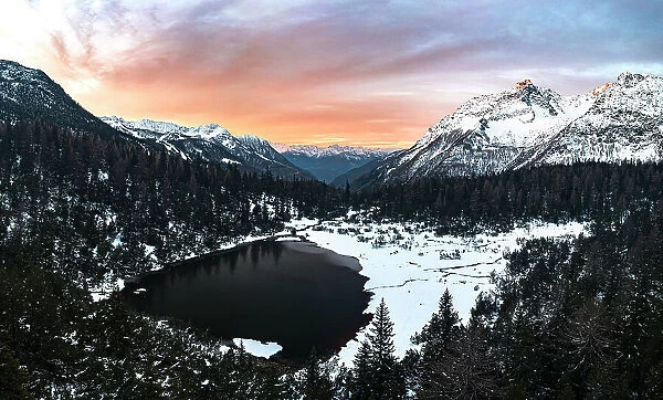 Aerial panoramic view of snowy forest and frozen lake Entova at sunrise, Valmalenco, Valtellina, Lombardy, Italy, Europe