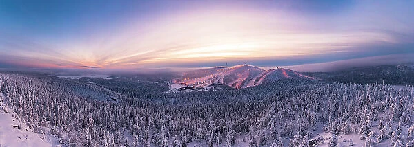 Aerial panoramic view of snowy forest and ski slopes under the dramatic sky at sunset, Ruka, Kuusamo, Northern Ostrobothnia, Lapland, Finland, Europe