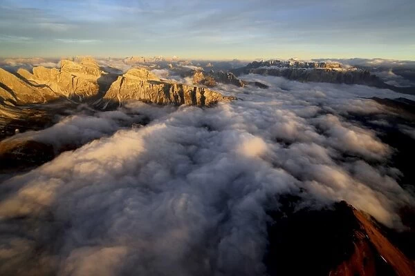Aerial shot of Sella Group Alps surrounded by clouds at sunset in the Dolomites, Val Funes