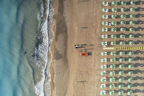 Aerial view of beach umbrellas and sunbeds in tidy rows during summer, Vieste
