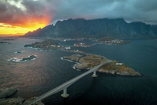 Aerial view of a bridge crossing the fjord under a dramatic sky at sunset, Reine Bay, Lofoten Islands, Nordland, Norway, Scandinavia, Europe
