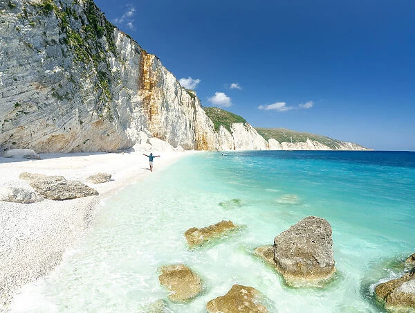 Aerial view of cheerful man with arms outstretched admiring the crystal sea at Fteri Beach, Kefalonia, Ionian Islands, Greek Islands, Greece, Europe