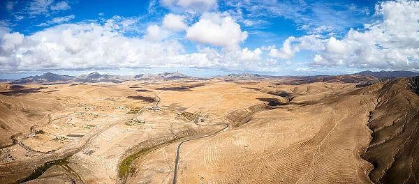 Aerial view of desert landscape and mountains crossed by asphalt road, Tefia