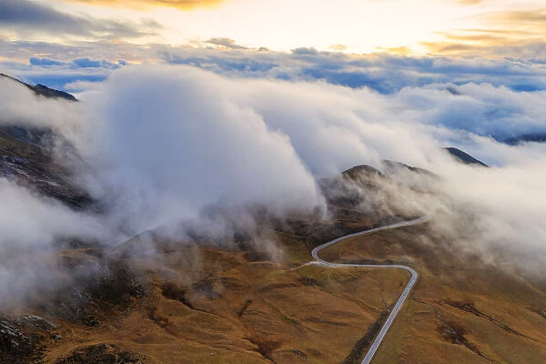 Aerial view by drone of fog over scenic road crossing Giau Pass in a sea of clouds at