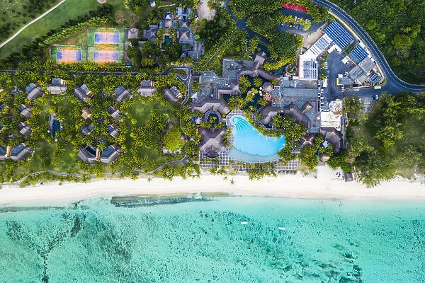 Aerial view by drone of luxury tourist resort on palm-fringed beach facing the tropical
