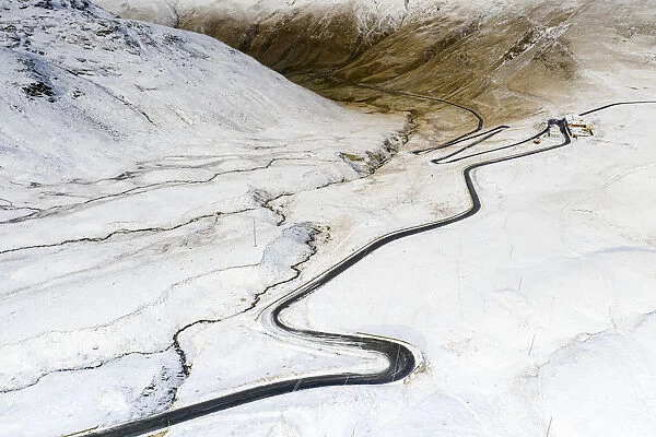 Aerial view by drone of S-shape road towards Stelvio Pass in the snowy landscape, Bormio