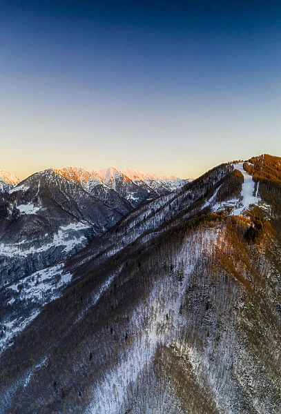 Aerial view by drone of ski slopes of Pian Delle Betulle and Alpe Paglio lit by sunset