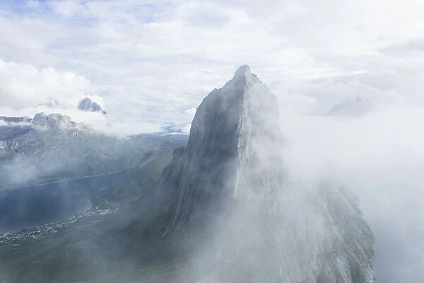 Aerial view of fog over the majestic Segla Mountain peak emerging from clouds