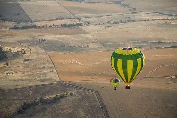 Aerial view of two hot air balloons floating over brown countryside near Northam in Western Australia, Australia, Pacific