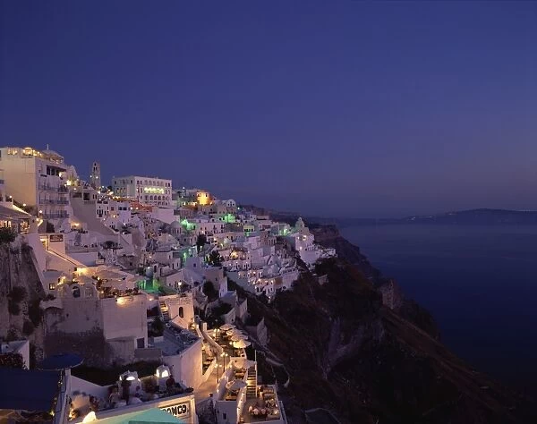 Aerial view over the illuminated houses of Fira Town at dusk