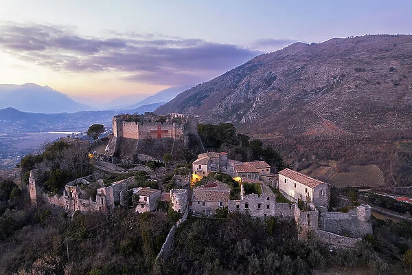 Aerial view of the medieval castle of Vicalvi, with red cross painted on the perimetral wall, overlooking the illuminated old village at dusk, Vicalvi, Frosinone province, Ciociaria, Latium region, Lazio, Italy, Europe