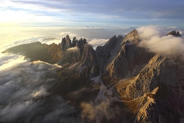 Aerial view of the mountain range of Odle surrounded by clouds in the Dolomites, Val Funes