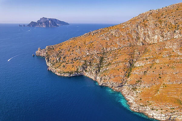 Aerial view of a rocky coast facing the blue water of the Tyrrhenian Sea with the island of Capri in the background, Amalfi Coast, Naples province, Campania region, South of Italy, Italy, Europe