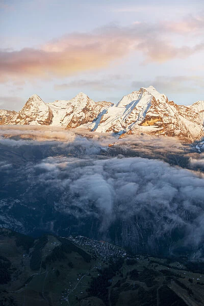 Aerial view of snowcapped peaks of Eiger, Monch and Jungfrau in fog at sunset