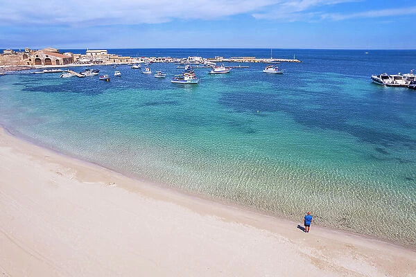 Aerial view of tourist standing in an empty white sand beach looking at the sea in front of the fishing village of Marzamemi, Marzamemi, Pachino municipality, Siracusa province, Sicily, Italy, Mediterranean, Europe