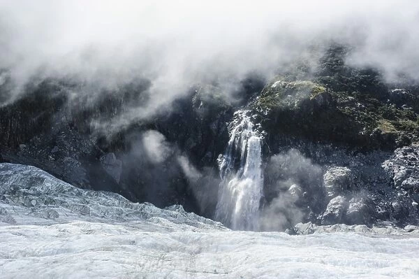 Aerial of a waterfall flowing into the icefield of Fox Glacier, Westland Tai Poutini National Park, South Island, New Zealand, Pacific