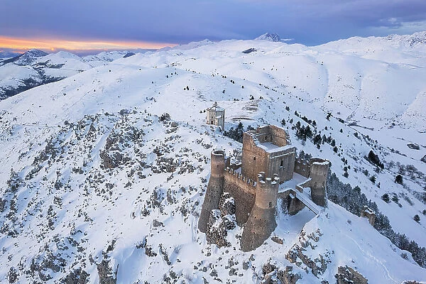 Aerial winter view of Rocca Calascio castle and the Santa Maria della Pieta church in the snowy landscape at dusk, Campo Imperatore, L'Aquila province, Abruzzo region, Italy, Europe