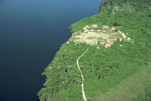 Aerial of a Xingu village and path beside a river in Brazil, South America