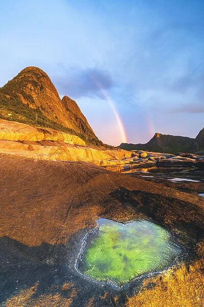 Algae inside rock formation on cliffs lit by rainbow during the midnight sun, Tungeneset