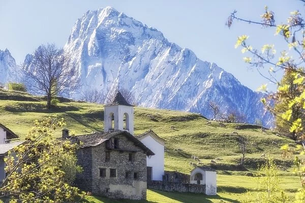 Alpine church framed by the snowy peak of Pizzo di Prata in spring, Daloo, Chiavenna Valley