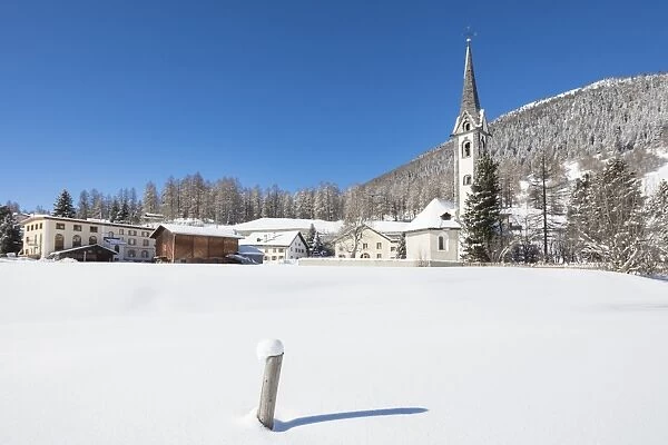 The alpine village covered with snow framed by blue sky, Cinuos, Canton of Graubunden
