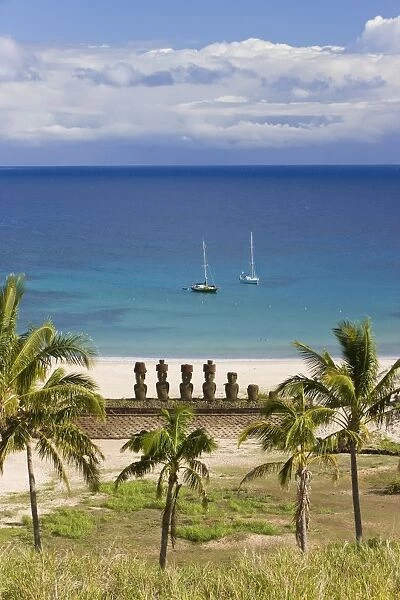 Anakena beach, yachts moored in front of the monolithic giant stone Moai statues of Ahu Nau Nau