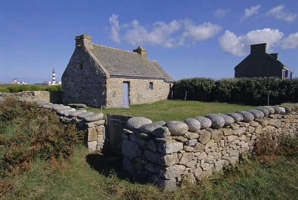 Ancient house with Creac h lighthouse behind on Ouessant Island, Brittany