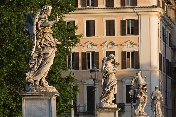 Angel statues on Ponte Sant Angelo with grand house behind, Rome, Lazio, Italy, Europe