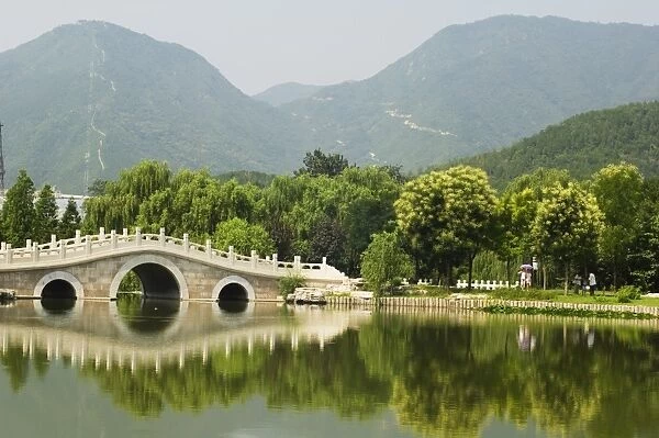 An arched stone bridge reflecting in a lake at Beijing Botanical Gardens