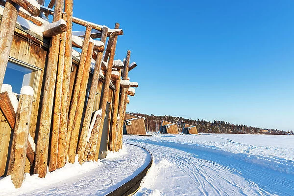 Architectural structure of Arctic Bath hotel made of logs on frozen Lule River with cutting-edge chalets in the background, Harads, Norrbotten, Swedish Lapland, Sweden, Scandinavia, Europe