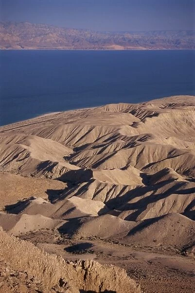 Arid hills on shore of Dead Sea, with Jordanian Mountains in the background