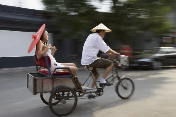 Asian woman (Chinese-Thai) riding in cycle rickshaw, Hutong District, Beijing
