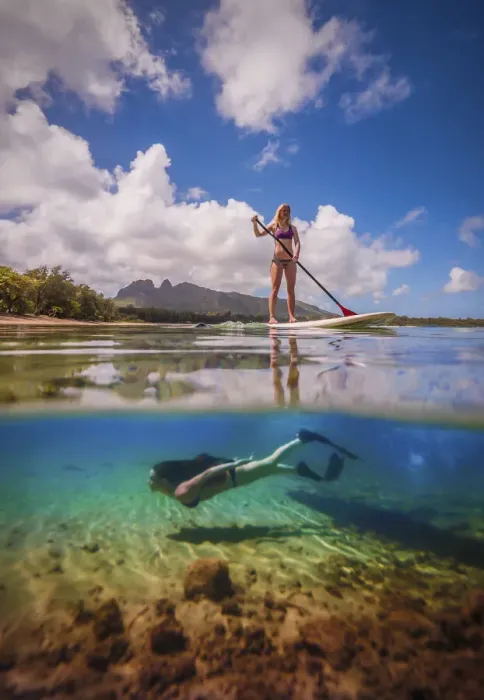 Framed Print : An athletic woman rides a stand-up paddle-board as another woman free-dives below her Framed Print : An athletic woman rides a stand-up paddle-board as another woman free-dives below her