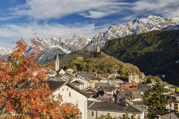 Autumn colors frame the village of Ardez surrounded by woods and snowy peaks, Engadine